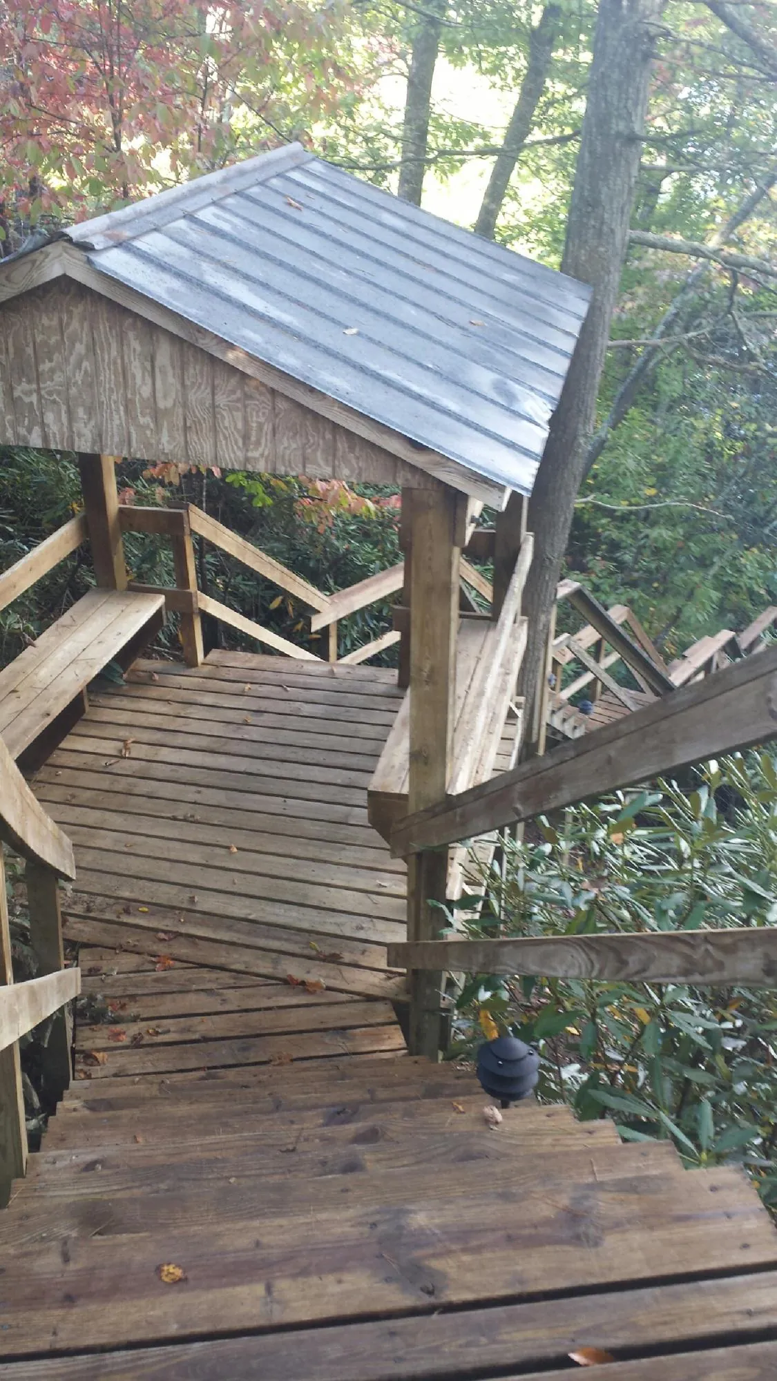 Metal roofed shelter over wooden steps on a wooded walkway — Skylight Repair & Installation work by our crew in Lost Nation