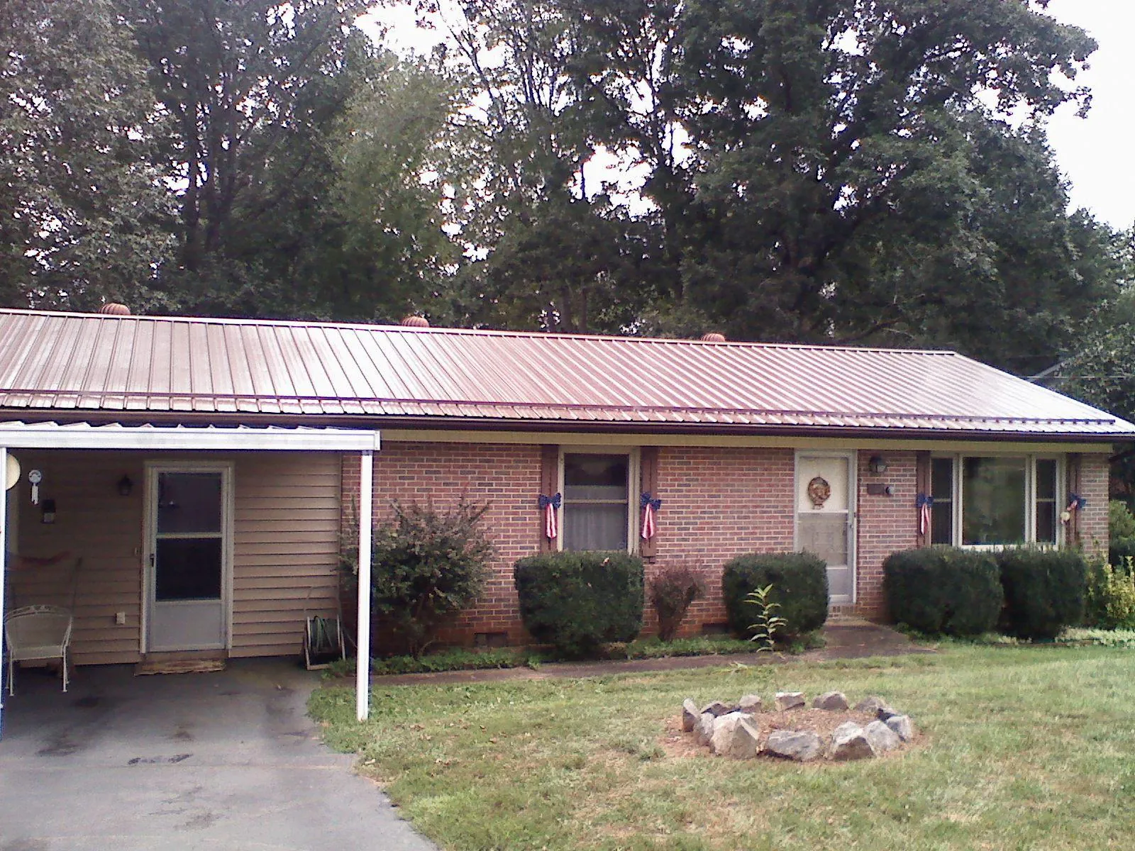 Bronze metal roof and carport on a brick ranch home — Roof Repair work by our crew in Lost Nation