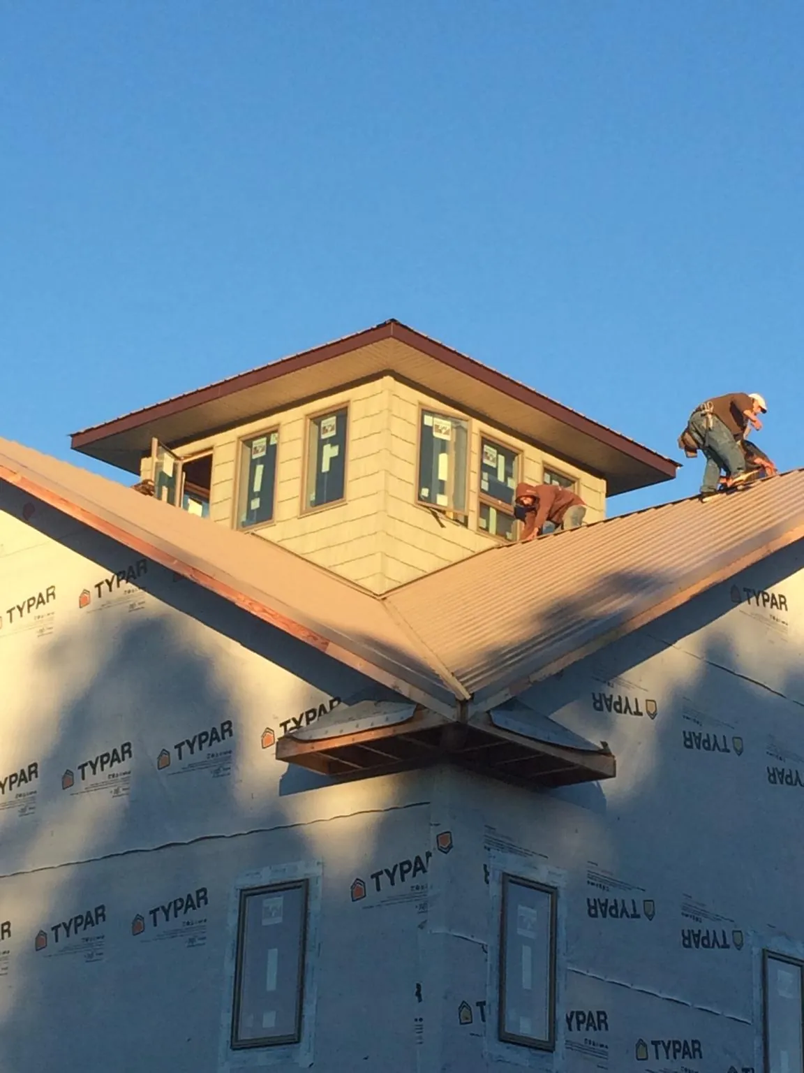Roofers working around a rooftop cupola on a new metal roof at sunset — Roof Waterproofing in Lost Nation by Roofing Brothers